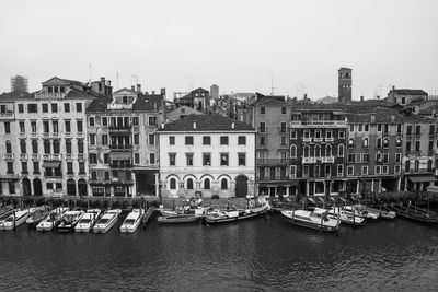 Boats moored in grand canal by buildings against clear sky