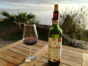 Glass of wine bottles on table against sky