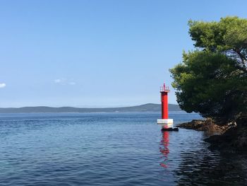 Lighthouse by sea against sky