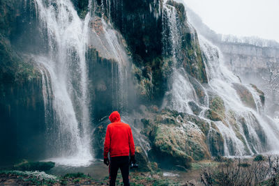 Rear view of man looking at waterfall