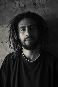 Portrait of young man standing against wall