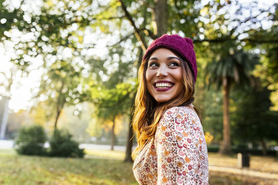 Happy young woman wearing wooly hat in a park in autumn