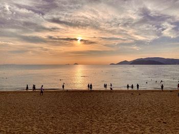 People on beach against sky during sunset