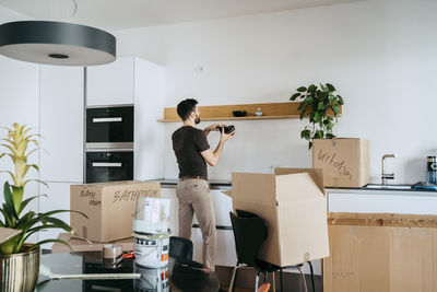 Man arranging bowls on shelf while standing in kitchen at new home