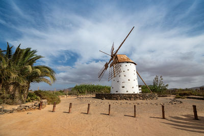 Traditional windmill on landscape against sky