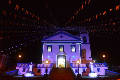 Low angle view of flags hanging on illuminated church at night