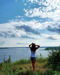 Woman standing on grass against sky