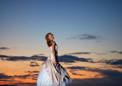 Woman standing against sky during sunset