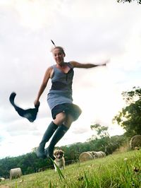 Young woman jumping on field against sky