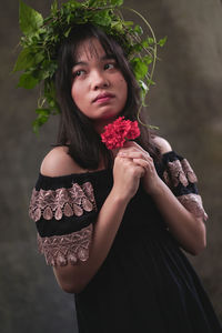 Portrait of a beautiful young woman holding red flower