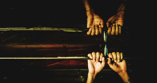 Cropped hands holding pole reflecting on glass