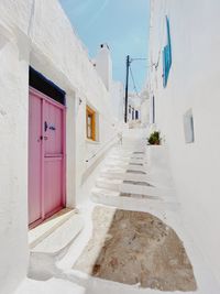 Lovely white picturesque traditional houses in greek island tinos in cyclades. pink door.