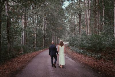 Rear view of couple walking on road in forest