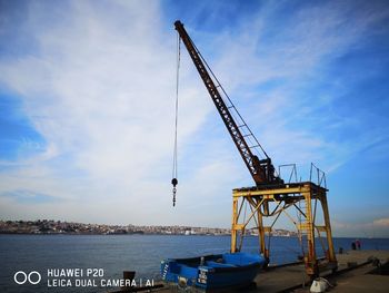 Cranes at commercial dock against sky