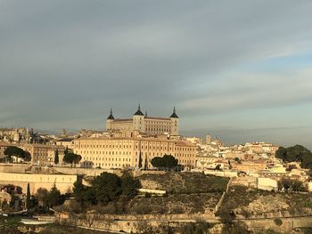 Buildings in city against cloudy sky