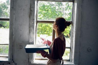 Side view of woman standing by window