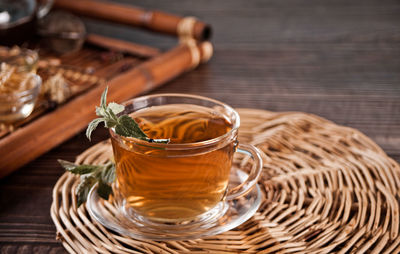 Cup of herbal mint tea with dry herbs on the tray.