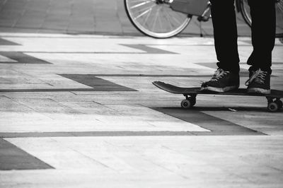 Low section of man standing over skateboard on footpath