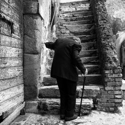 Rear view of man walking on staircase against building