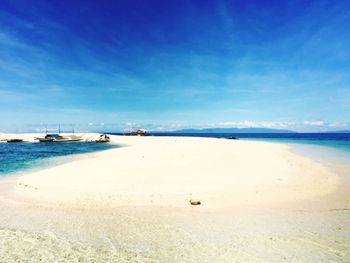 Scenic view of beach against blue sky during sunny day