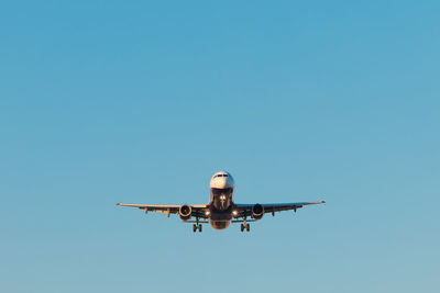 Low angle view of airplane against clear blue sky