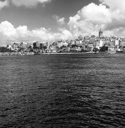 Scenic view of river by cityscape against sky