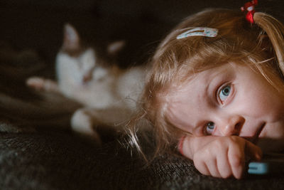 Little girl laying in front of cat