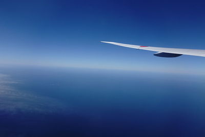 Airplane wing against clear blue sky