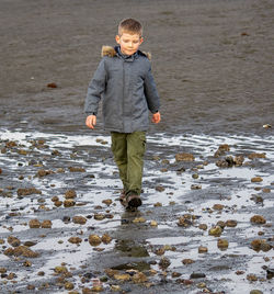 Boy walking at wet beach