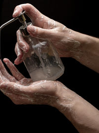 Close-up of hand holding water against black background