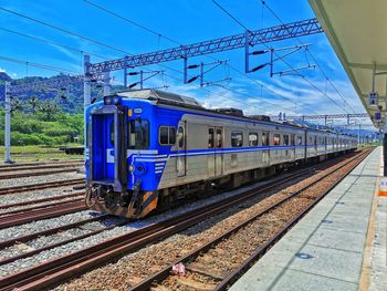 Train on railroad track against blue sky