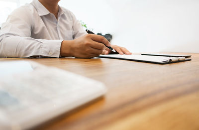 Midsection of man using mobile phone on table