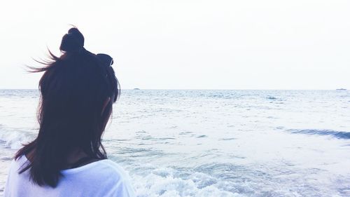 Rear view of silhouette woman on beach against clear sky