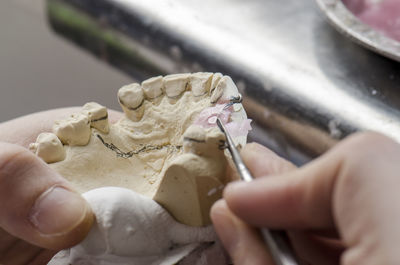 Cropped hands of person working on dentures