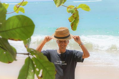 Portrait of man seen through leaves at beach