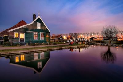 House reflecting on river against sky during dusk