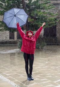 Full length of woman standing with umbrella during rainfall