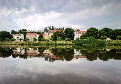 Reflection of trees and buildings in lake against sky