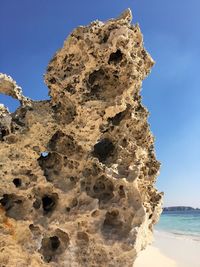 Rock formation on beach against clear blue sky