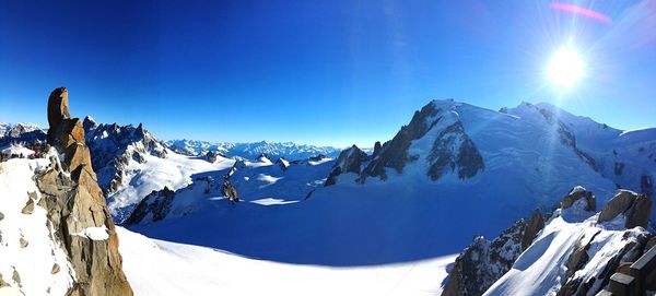 Panoramic view of snowcapped mountains against blue sky