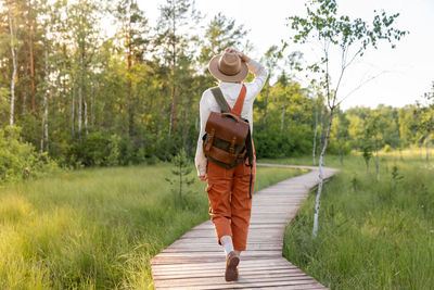 Woman botanist on ecological hiking trail outdoors. naturalist exploring wildlife, ecotourism