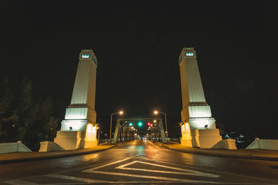 Illuminated city street against sky at night