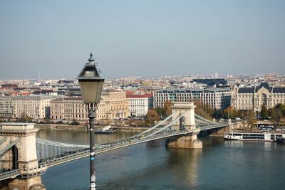 Bridge over river in city against clear sky