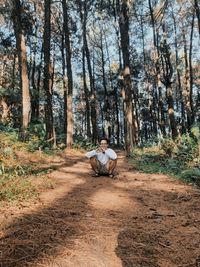 Rear view of man sitting on road in forest