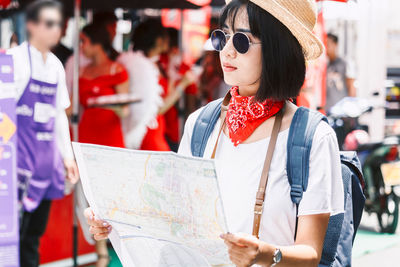 Young woman holding map while standing in city