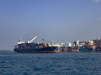 Commercial dock by sea against clear sky