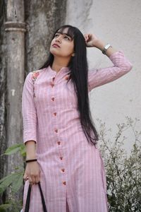 Full length of woman standing against pink wall