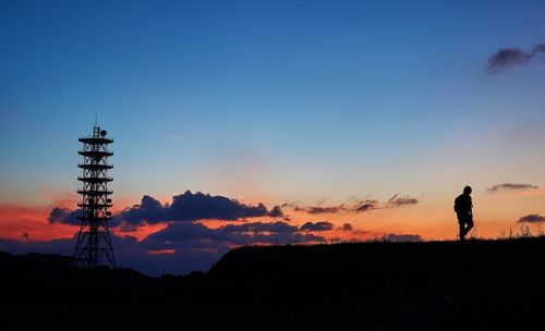 Silhouette man walking on field against sky during sunset