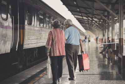 Rear view of people walking on railway station platform