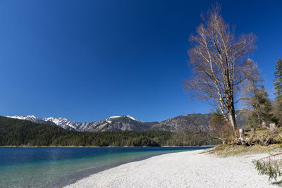 Scenic view of lake and mountains against clear blue sky